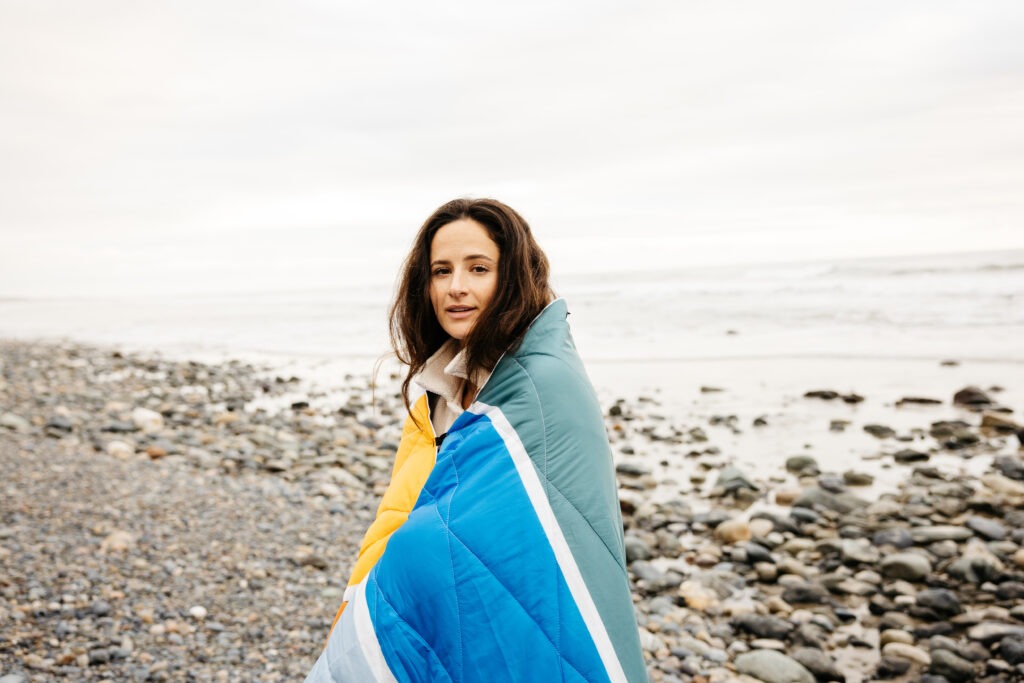 Woman on a beach with a Nomadix blanket wrapped around her